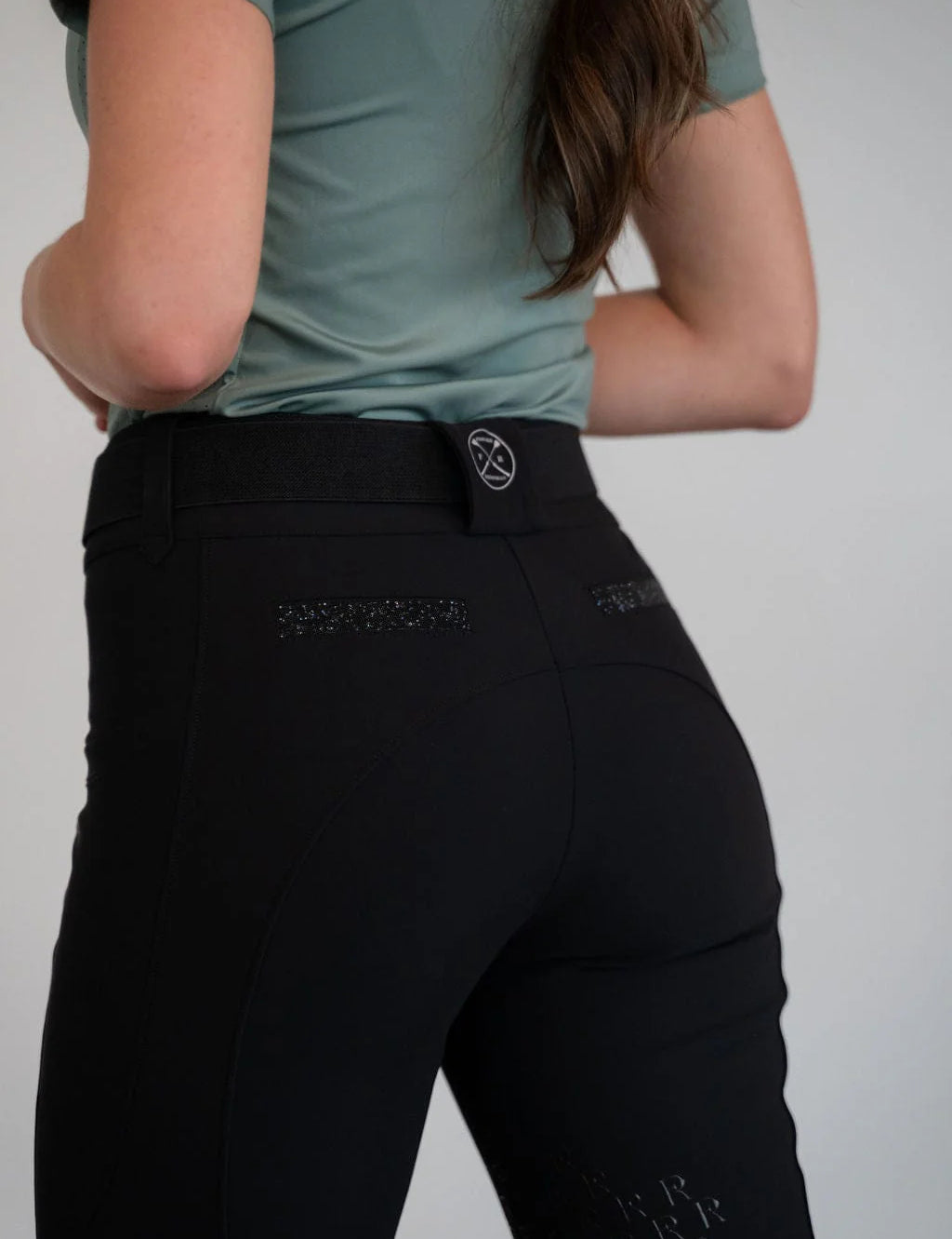 Back view of a model wearing the black Free Ride PRO Knee Patch Breeches in a studio setting