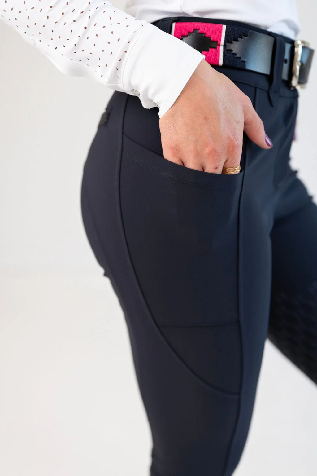Close-up view of a model showing the cell phone pocket on the navy Free Ride Sparkle PRO Full Seat Breeches on a plain background
