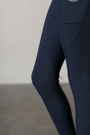 Close-up view of the silicone knee patch on the navy Free Ride Youth Lux Full Seat Breeches on a plain background