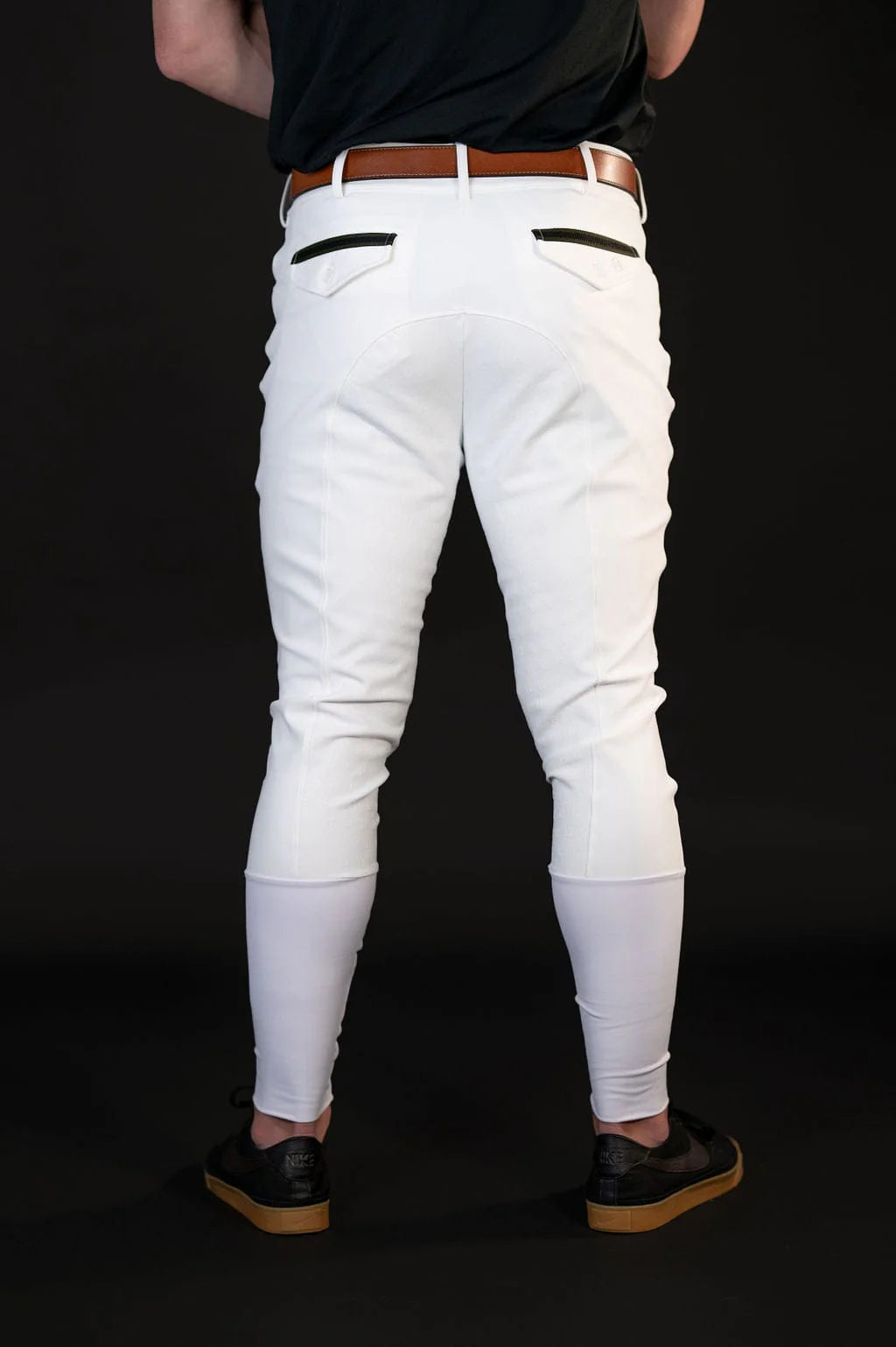 Back view of a male model wearing the white Free Ride Men's PRO Knee Patch Breeches on a black background