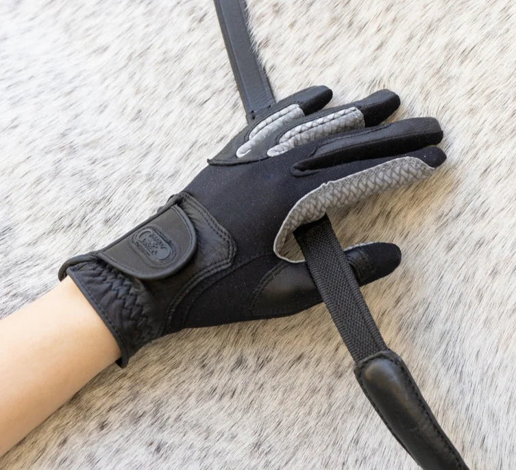 Person wearing the Correct Connect Oil-Tac Copper Tech™ Leather Premium Riding Glove in black while holding a rein against a gray horse