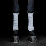 Front view of a black horse wearing a pair of black Incrediwear Circulation Exercise Bandages on a black background