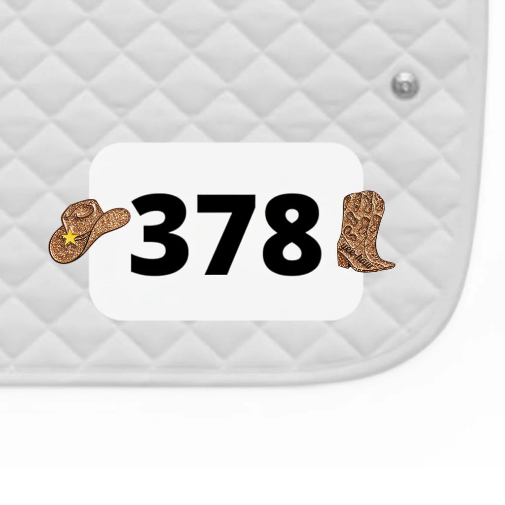 Side view of a white pad with numbers 378 and a pair of Cowgirl Dubois Cheval Number Pin Charms on a white background