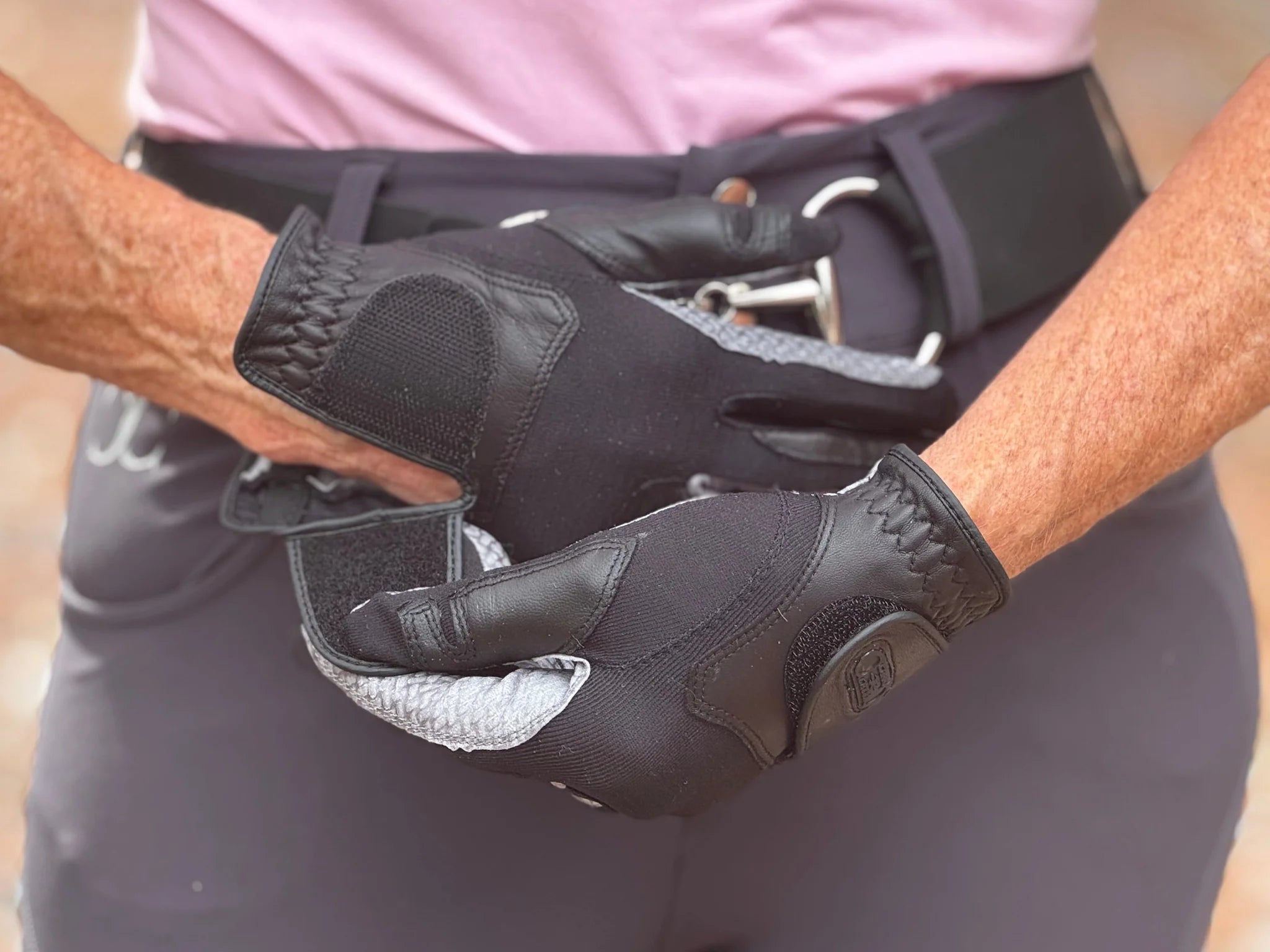 Close-up of a person putting on a pair of Correct Connect Oil-Tac Copper Tech™ Leather Premium Riding Gloves in black