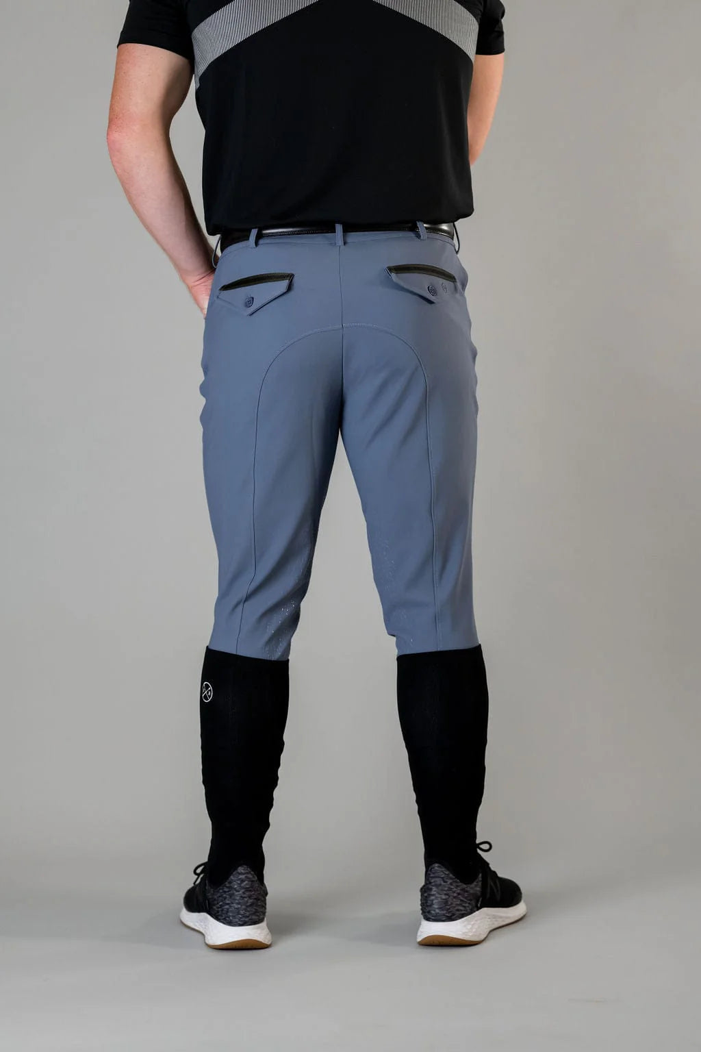 Back view of a male model wearing the blue Free Ride Men's PRO Knee Patch Breeches on a plain background