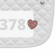 Side view of a white pad with numbers 378 and a Disco Heart Dubois Cheval Number Pin Charm on a white background