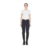 Full body view of a model wearing the Equestro Women's Slim Fit Grip Breeches With Logo in navy , a white tshirt, and black boots on white 