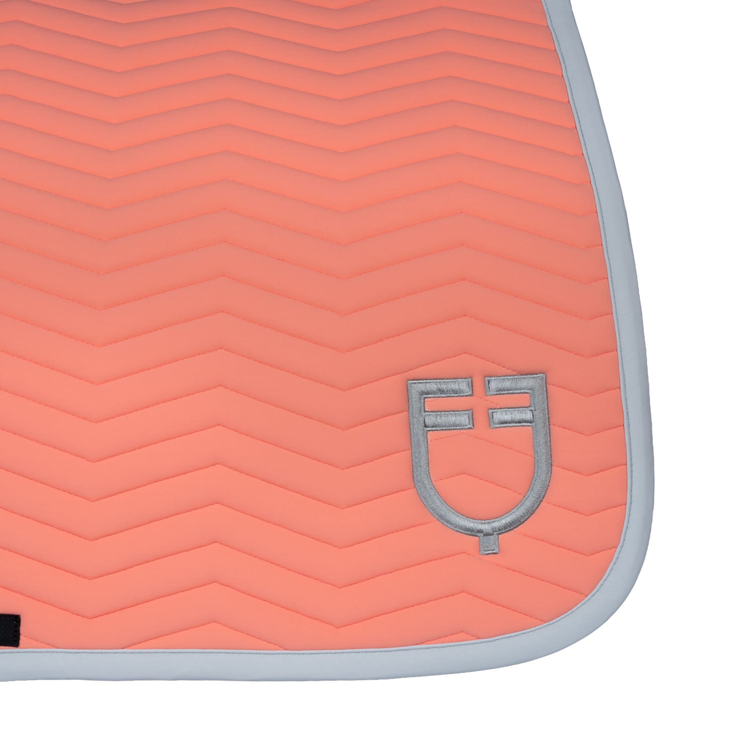 Close up view of the logo detal on the botttom corner of the Equestro Wave Quilting Jump Saddle Pad In Technical Fabric in a coral color on a white background