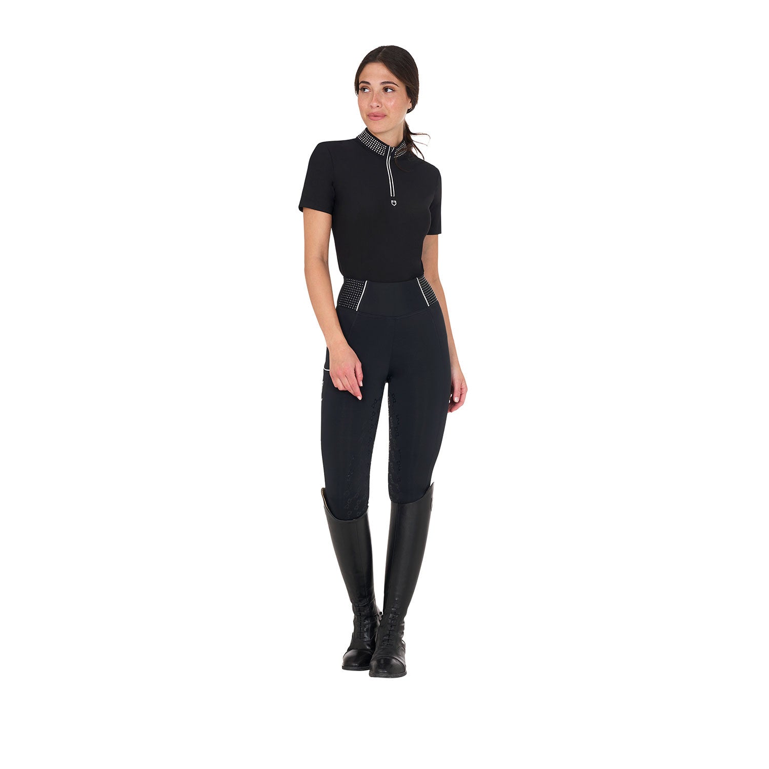 Full body view of model wearing the Equestro Women's Slim Fit Training Polo Shirt With Zip And Collar Rhinestones in black, black breeches, and black tall boots on a white background