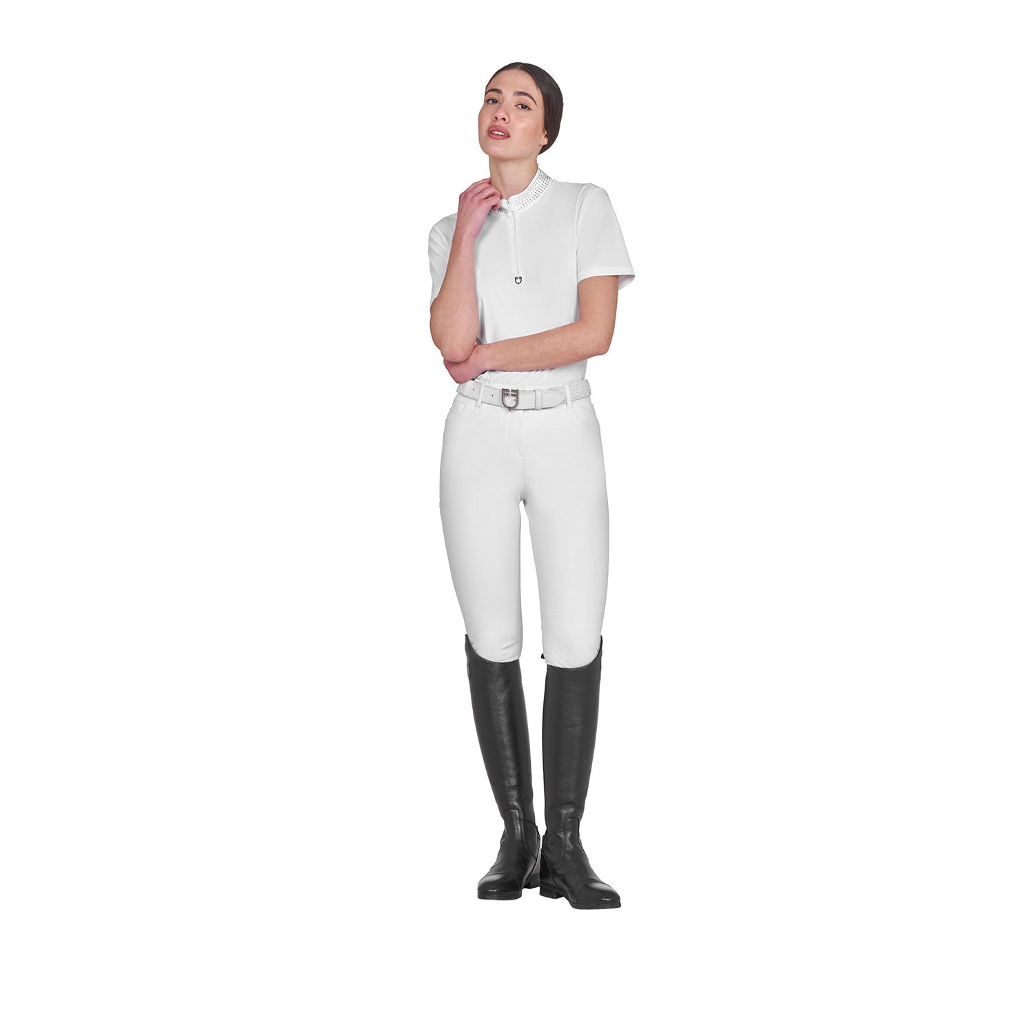 Full body view of model wearing the Equestro Women's Slim Fit Training Polo Shirt With Zip And Collar Rhinestones in white, white breeches, and black tall boots on a white background