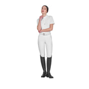 Full body view of model wearing the Equestro Women's Slim Fit Training Polo Shirt With Zip And Collar Rhinestones in white, white breeches, and black tall boots on a white background