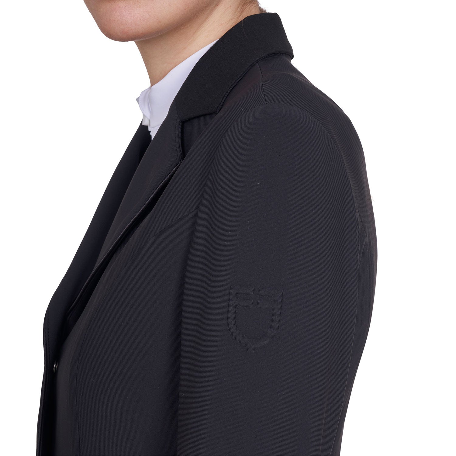 Side view of the embossed logo of the Equestro Women's Competition Jacket With Zip And Buttons in black on a white background