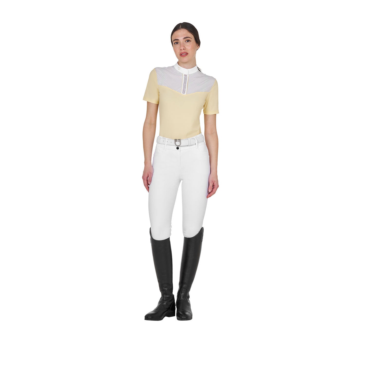 Full body front view of model wearing the Equestro Women's Slim Fit Competition Polo Shirt With Silk-Like Fabric Inserts in white and yellow, white breeches, and black tall boots on a white background