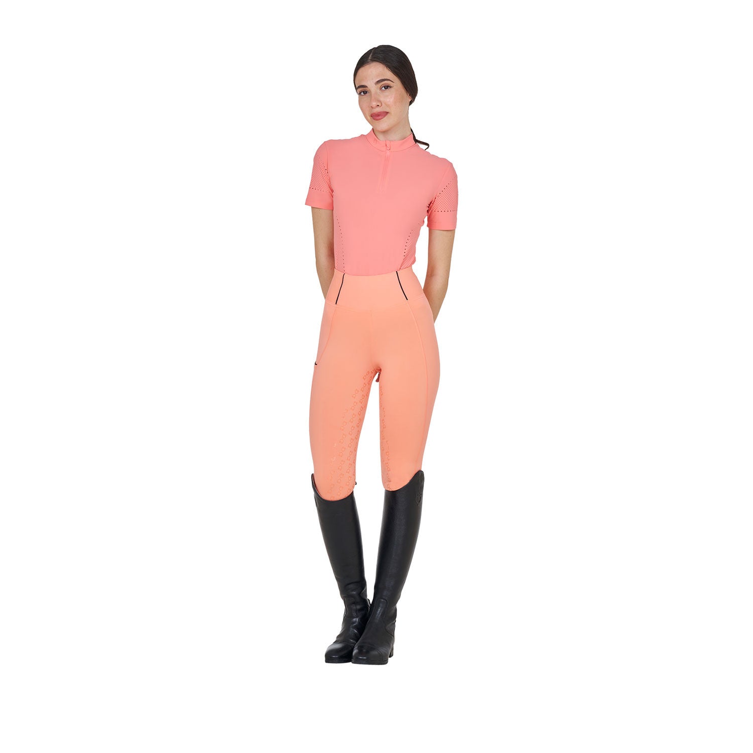 Full body front view of model wearing the Equestro Women's Training T-Shirt In Technical Fabric With Micro-Holes in pink, orange tights, and black tall boots on a white background