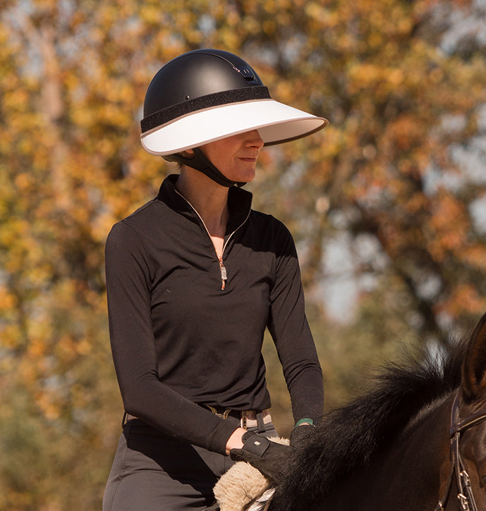 Side view of a female model wearing the white/mocha EquiVisor Sport Sun Visor while riding a horse