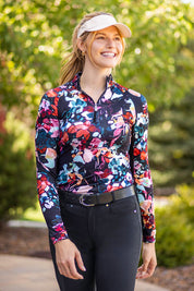 Front view of a female model wearing the Black Watercolor Floral Kastel 1/4 Zip Long Sleeve Sun Shirt while walking on a path outside