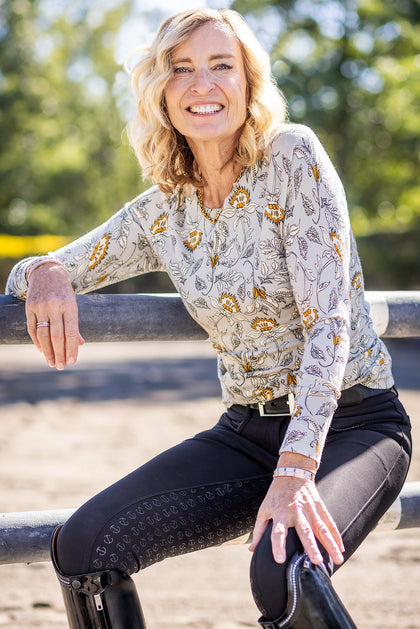 Front view of a female model wearing the Vintage Dove Kastel Crewneck Sweater while sitting on a fence