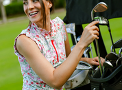 Front view of a model wearing the Red Scandinavian Berries Kastel 1/4 Zip Ruffle Tank while picking golf clubs out of a golf bag