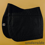 Side view of the underside of the black Ecogold Secure Dressage Pad on a yellow background