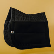 Side view of the black Ecogold Secure Dressage Pad on a yellow background