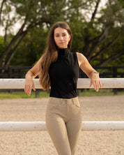Front view of model leaned up against a white fence wearing the Equisite Blaire Perforated Sleeveless Shirt in Jet Black