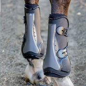 Close-up back view of a horse wearing the black Professional's Choice Pro Performance Open Front Boots while standing on arena footing
