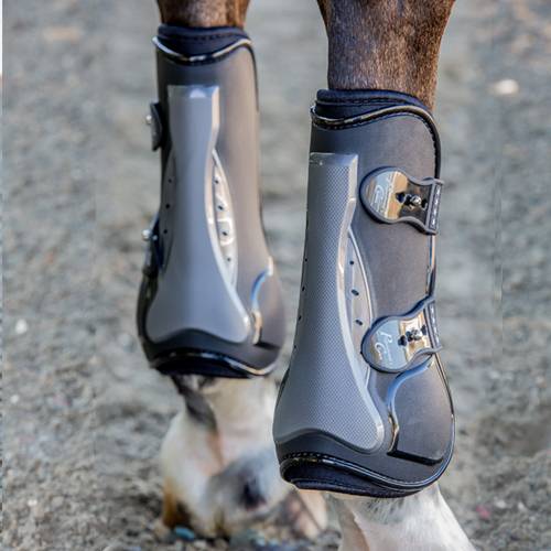 Close-up back view of a horse wearing the black Professional's Choice Pro Performance Open Front Boots while standing on arena footing