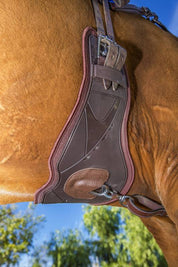 Professional’s Choice VenTECH contoured monoflap girth in chocolate attached to saddle on horse, showing contoured shape and center D-ring