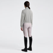 Angled back full length view a model wearing the Cavalleria Toscana Jersey Zip Sweatshirt In Belgian Block, light colored breeches, and black tall boots.