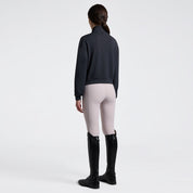 Angled front full length view a model wearing the Cavalleria Toscana Jersey Zip Sweatshirt in Charcoal, light colored breeches, and black tall boots.