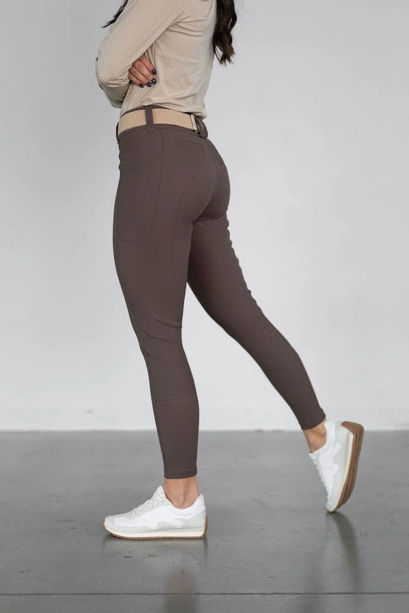 Side view of a model wearing the brown Free Ride PRO Full Seat Breeches on a plain background