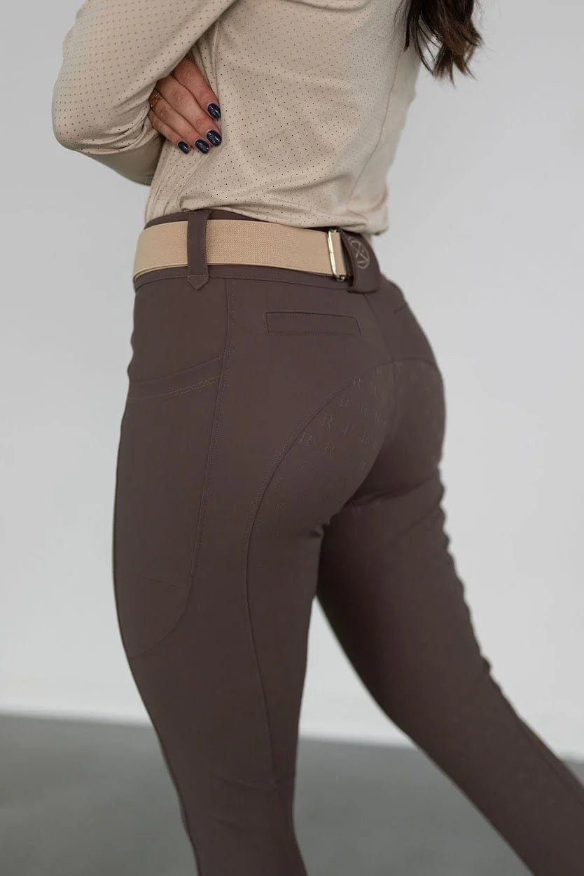 Close-up side view of a model wearing the brown Free Ride PRO Full Seat Breeches on a plain background