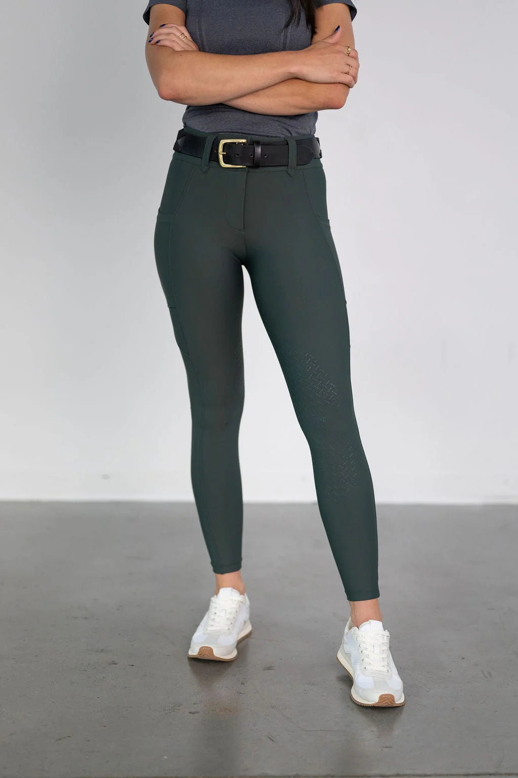 Front view of a female model wearing the green Free Ride Lux Knee Patch Breeches in a studio setting