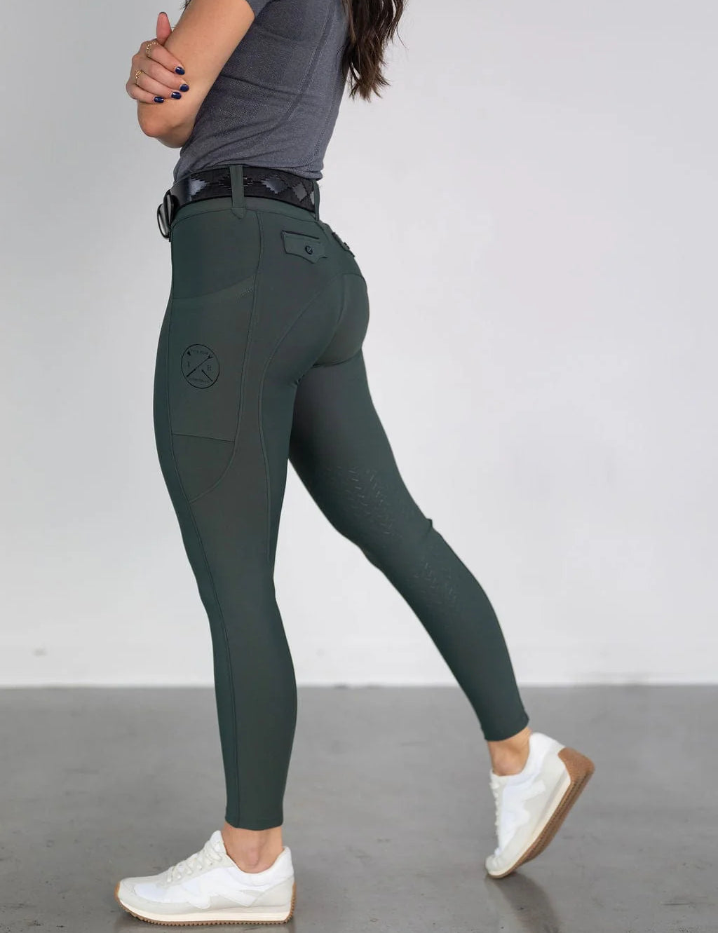 Side view of a female model wearing the green Free Ride Lux Knee Patch Breeches in a studio setting