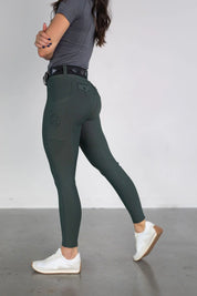 Side view of a female model wearing the green Free Ride Lux Knee Patch Breeches in a studio setting