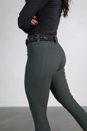 Side view of a model wearing the green Free Ride PRO Full Seat Breeches on a plain background