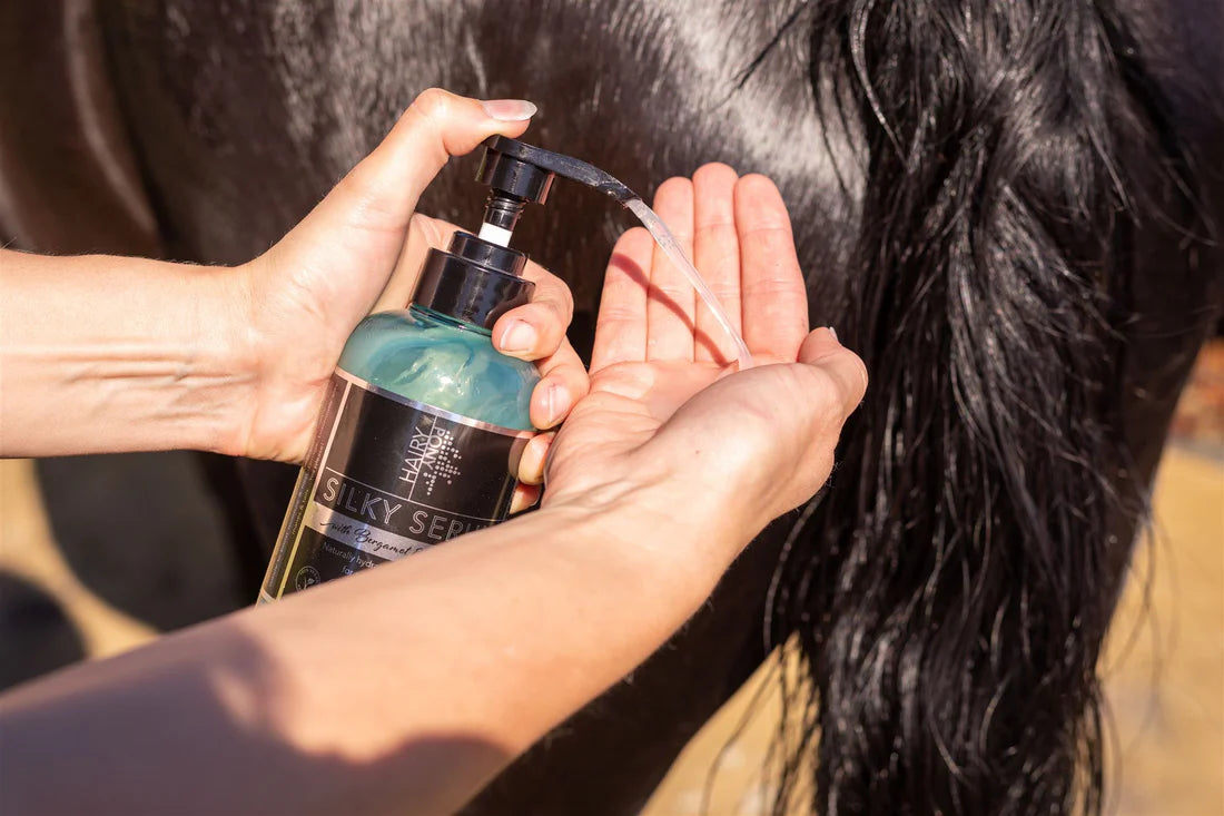 Hand dispensing Hairy Pony Silky Serum onto palm beside a horse’s dark tail