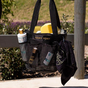 View of the Hairy Pony Horse Wash Bay Bag filled with bathing supplies and a fence in the background