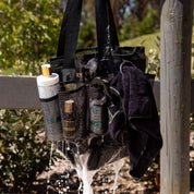 View of the Hairy Pony Horse Wash Bay Bag hanging on a fence and filled with bathing supplies