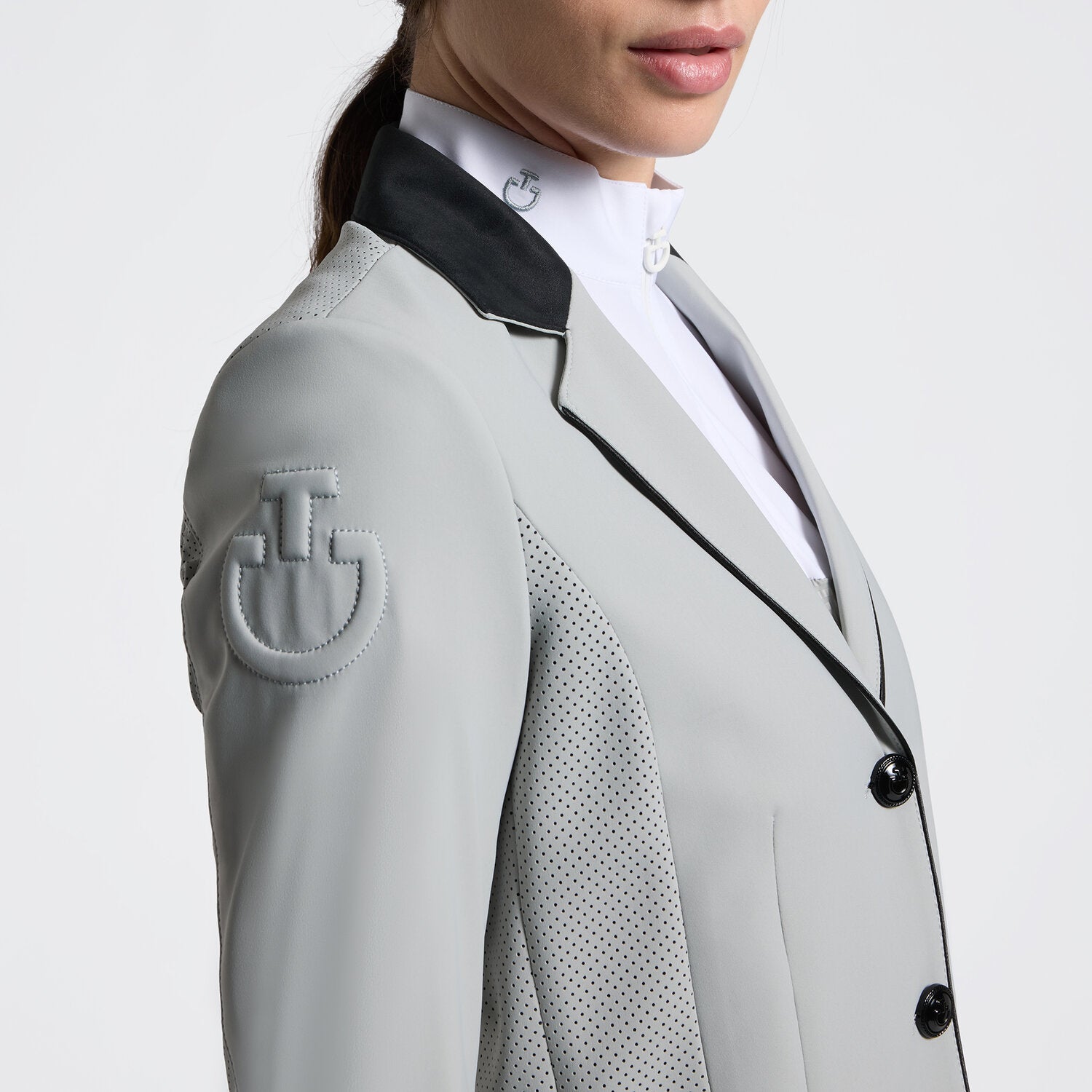 Close-up angled front view of a female model wearing the gray Cavalleria Toscana GP Perforated Riding Jacket on a plain background