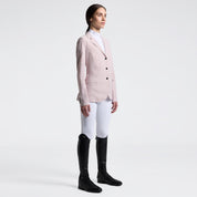 Full body angled front view of a female model wearing the pink Cavalleria Toscana Raw Cut Competition Jacket and white breeches on a plain background