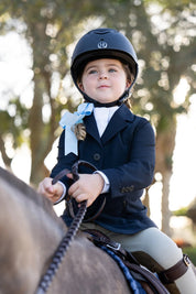 Child wearing Harmony Jr. 2.0 Mesh Show Coat in navy while riding a horse outdoors, front view with riding helmet