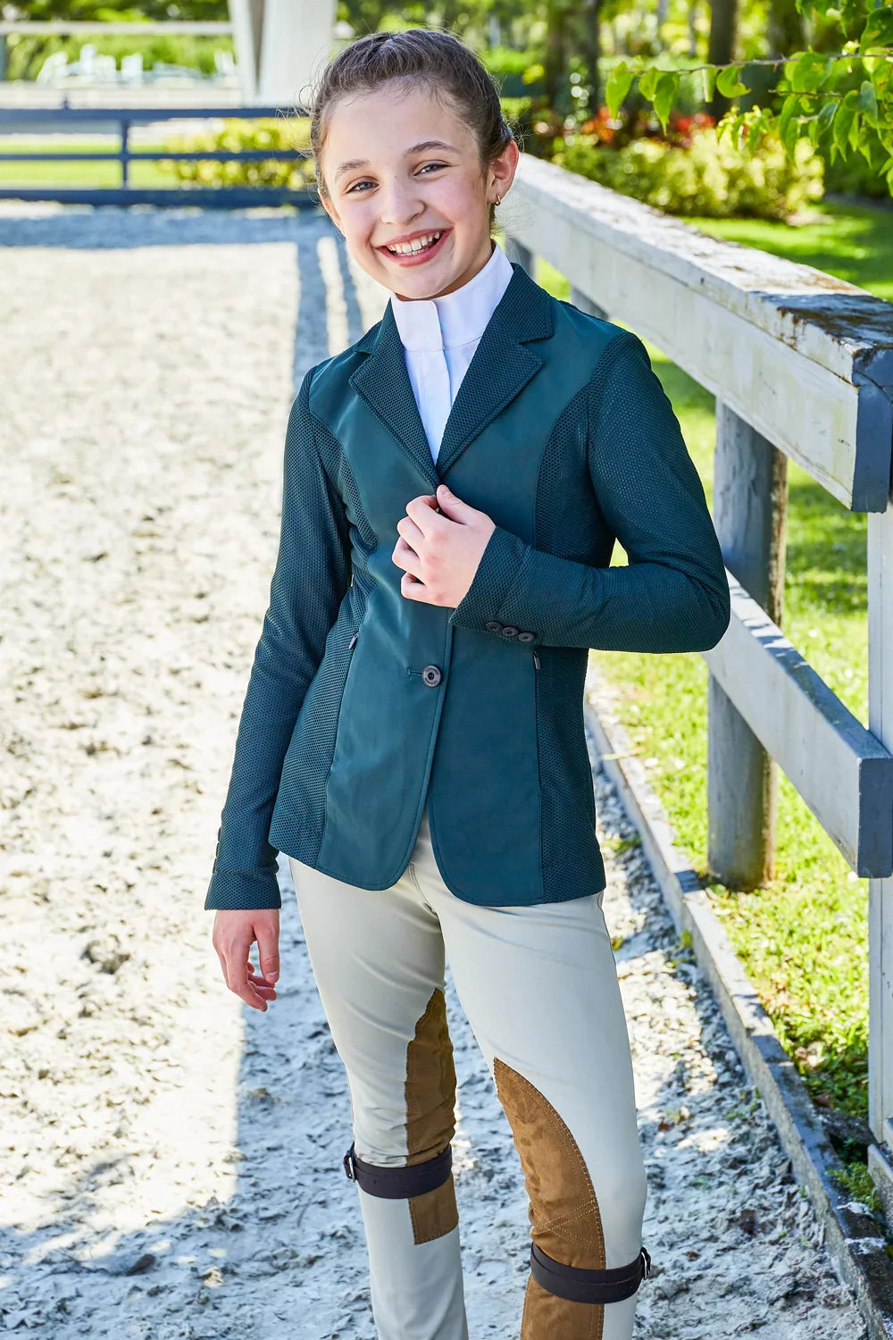 Outdoor photo of the RJ Classics Harmony Jr. 2.0 Mesh Show Coat in Green Gables, showing a notched lapel, three-button front, and mesh sleeves and side panels, worn over a white high-collar show shirt with tan knee-patch breeches.