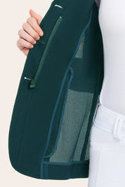 Close-up of the green mesh show coat opened to show an inside zip pocket and mesh lining, worn over a white top and white breeches.