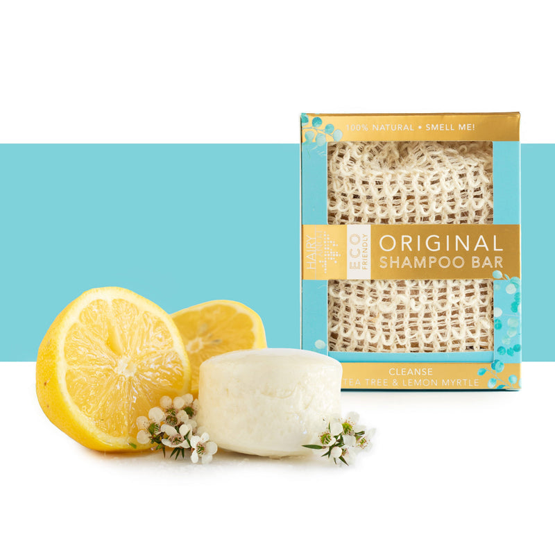 View of the Tea Tree and Lemon Myrtle Hairy Pony Eco-Friendly Shampoo Bar with a lemon and white flowers on a blue and white color block background