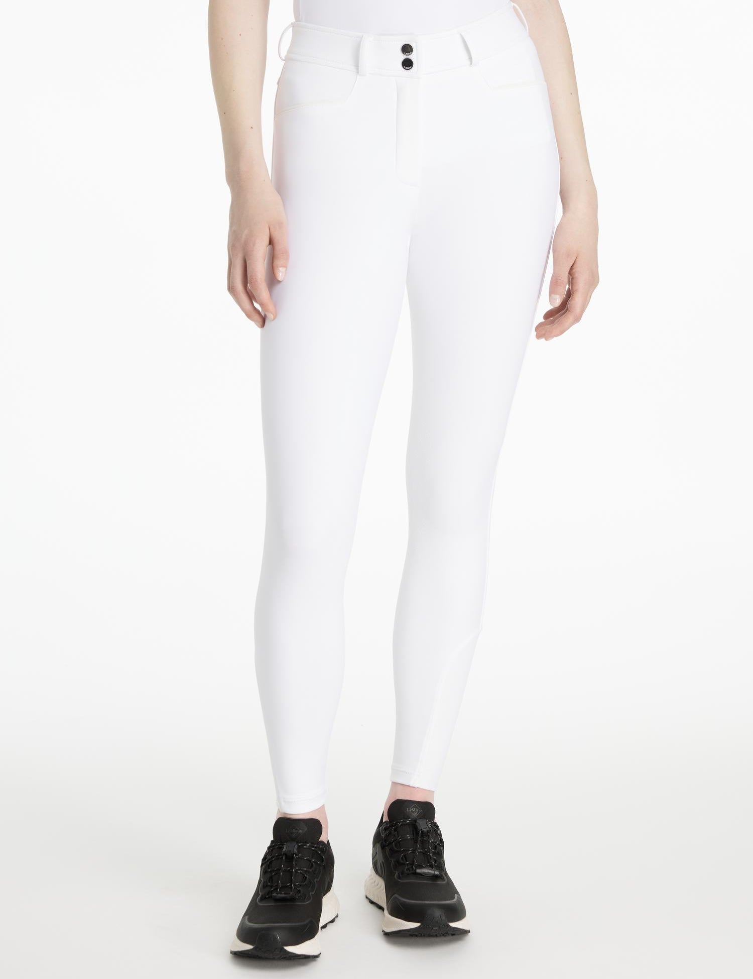 Model wearing LeMieux Isabelle Full Seat Breeches in White with black athletic shoes