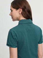 Close-up back/side view of the LeMieux Pixie polo shirt in jungle green showing the collar, sleeve piping, and LeMieux logo at the upper back against a light gray background.