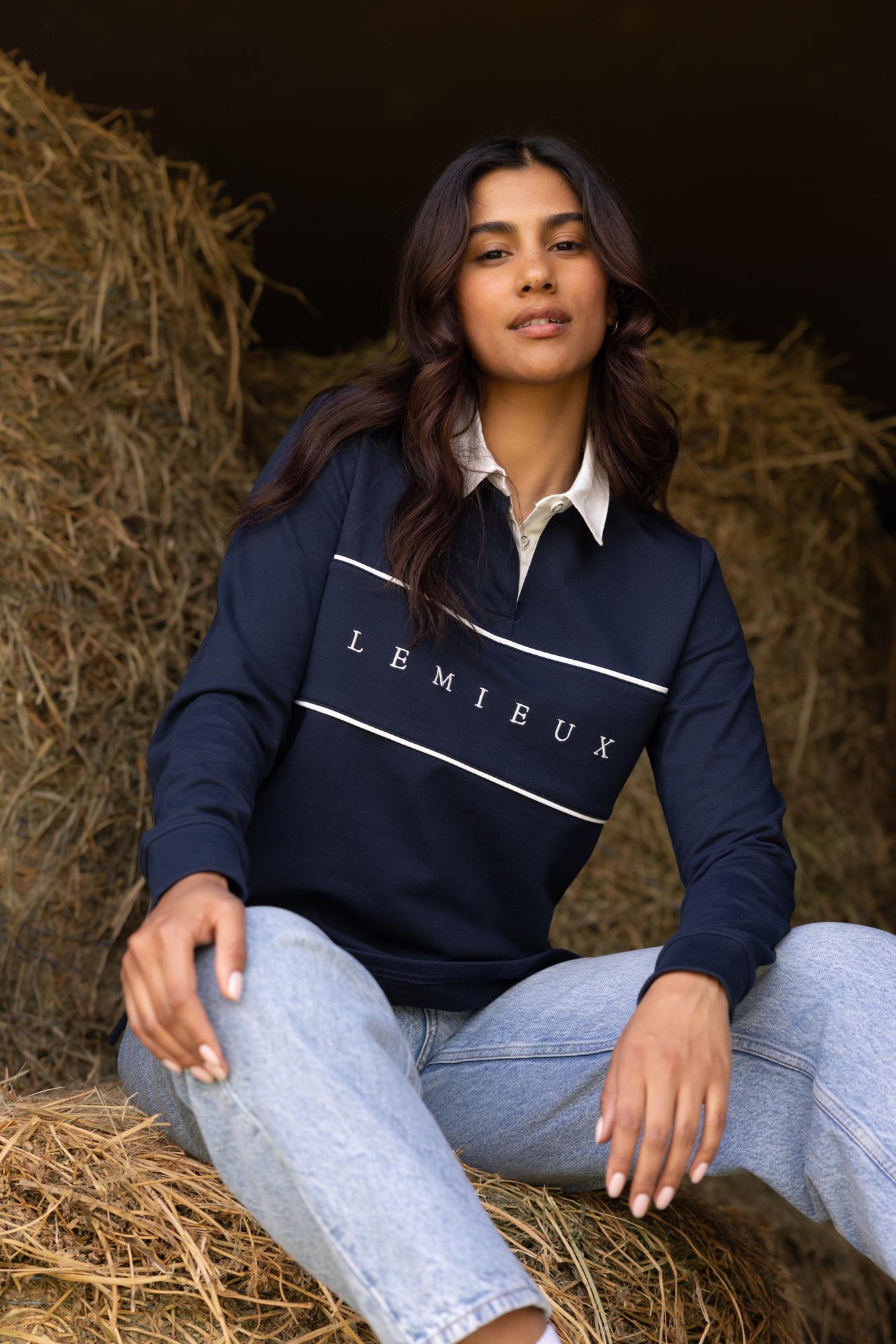 Navy Rochelle Rugby Shirt with white collar and chest piping, worn seated on hay bales.