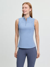 LeMieux Airflow sleeveless base layer in powder blue with a quarter-zip high collar, shown on a model wearing blue riding tights against a light gray background.