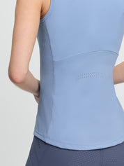 Close-up back view of the LeMieux Airflow sleeveless base layer in powder blue showing a perforated panel at mid-back and a textured side panel, worn with blue riding tights against a light gray background.
